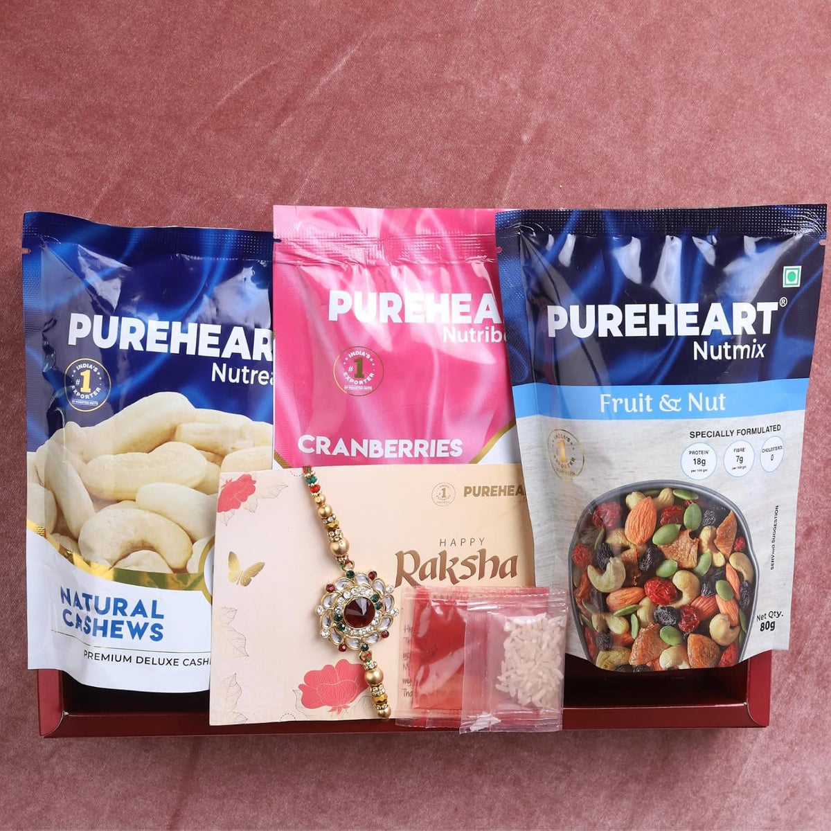 PUREHEART Rakhi Gift Hamper- Natural Cashews, Fruit & Nut Nutmix and Cranberries(80g, each) with Floral Rakhi for Brother, Gift Card, Pooja Rice, Kumkum - Crunchy Dry Fruits and Nuts